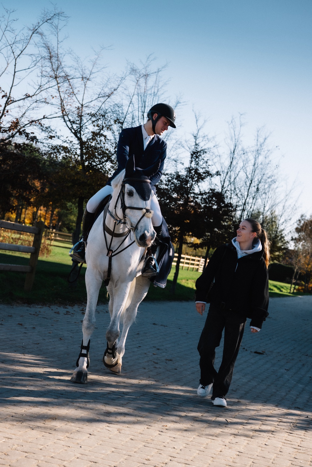 Liesl walking beside a grey horse and rider at APG Stables